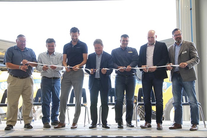 Cutting the ribbon to officially open the new Mazergroup location in Moosomin. From left are Moosomin Mayor Larry Tomlinson, Randy Tye, VP of Inventory Management, Chris Finley, VP of Parts and Service, Bob Mazer, the President and CEO of Mazergroup cutting the ribbon, Andrew Marshall, Canadian Sales Manager for New Holland, Brad Tarr, the VP of Sales and Marketing, and Wally Butler, the VP of Finance and Administration.