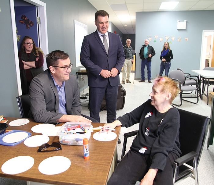 Moosomin MLA Steven Bonk, standing, and Saskatchewan Social Services Minister Paul Merriman, seated, visited the Pipestone KinAbility Centre in Moosomin Thursday. Minister Merriman chats with Brenda Sopp as the two share a few laughs.