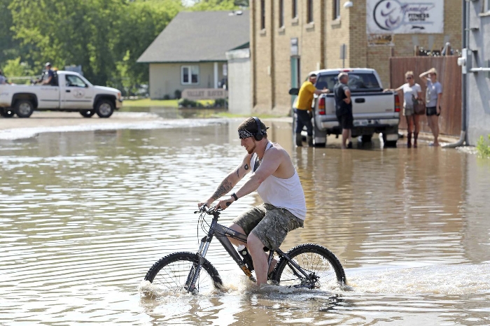 Jesse Hunt walks his bike through flood water inundating Main Street in Minnedosa after heavy downpours this summer caused widespread flooding. The swollen Little Saskatchewan River overflowed into downtown Minnedosa flooding several businesses and residences.