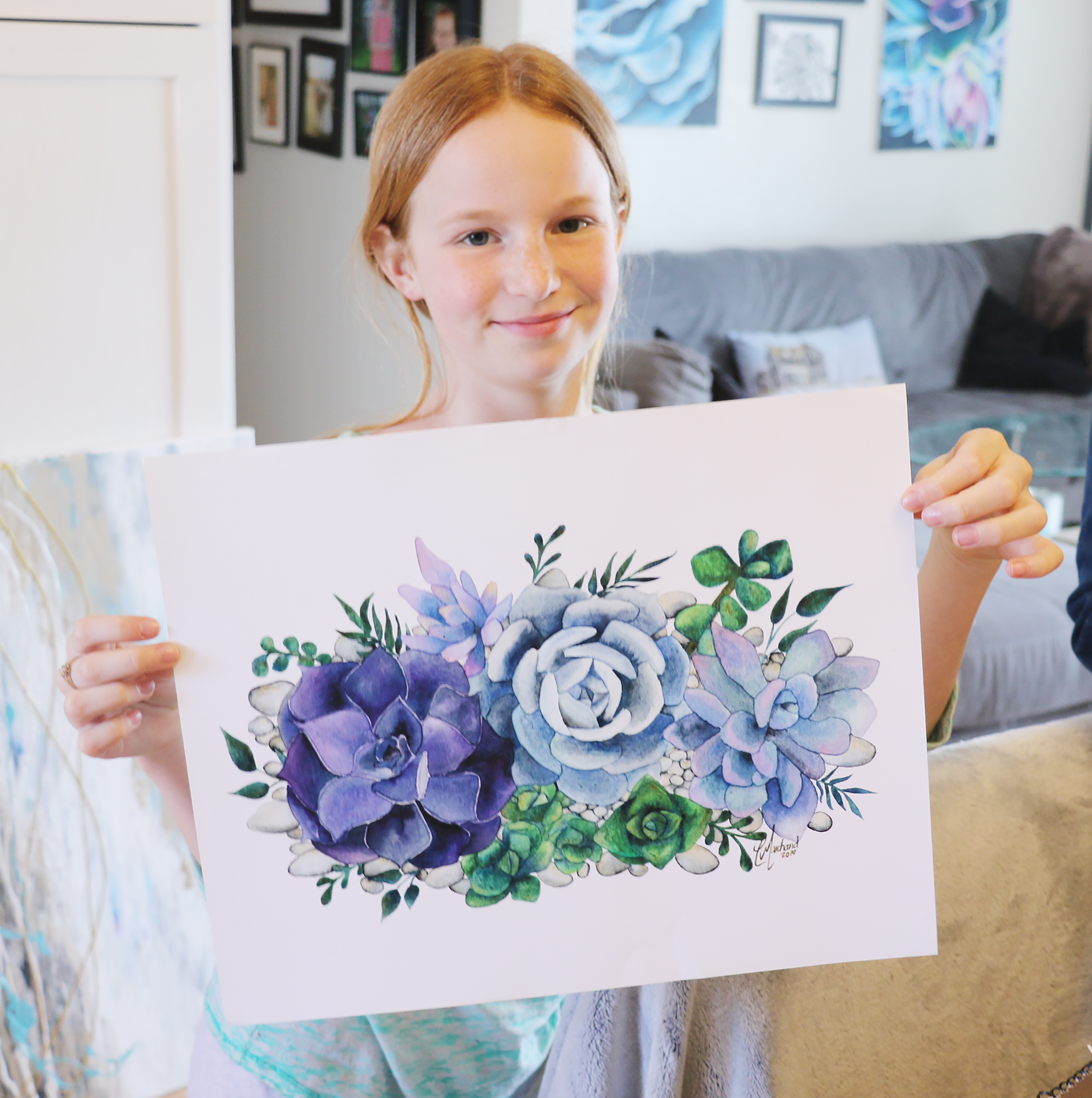 Alli Urschel, daughter of Chylisse Marchland, shows off one of her mothers traditional watercolour floral pieces.