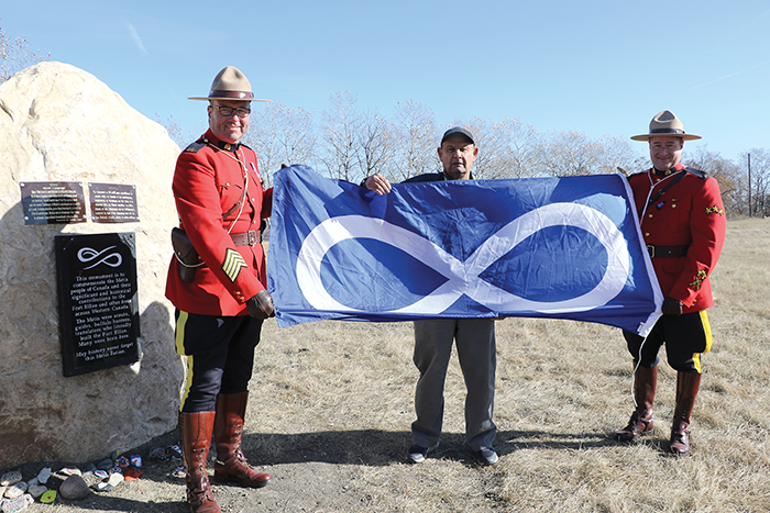 S/Sgt. Matt Lavallee and Corporal Brett Church of Prairie Mountain RCMP hold the Mtis flag with President of MMF Fort Ellice Terry Haney.