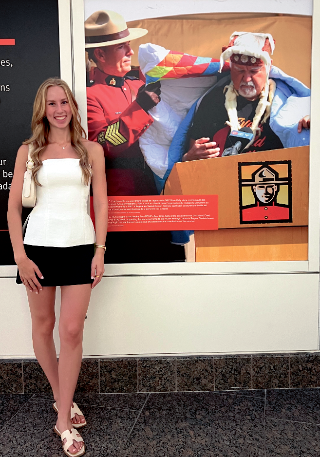 Ashley Bochek with her photo on display at the Canadian Museum of History. The photo shows sculptor Stan Hunt being draped in a star blanket.