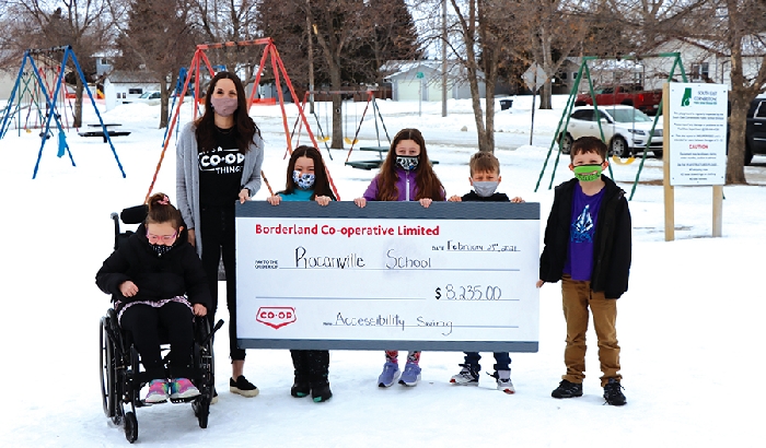 Borderland Co-op Community Relations Manager Savannah Roden presents Rocanville School students (left to right) Sofia Laidlaw, Lilly Jackson, Ella Bock, Corbin Minty, and Odin Rosti with a cheque for $8,235 to go towards the schools wheelchair swing project.
