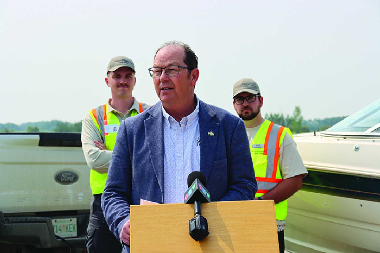Minister of Environment Travis Keisig speaking at the Inspection Station east of Moosomin Thursday. Behind, two aquatic inspectors for the Moosomin Inspection Station east of town at the weigh scales